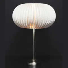 Lampe avec abat-jour sphérique en carton blanc plissé, sur pied métallique.