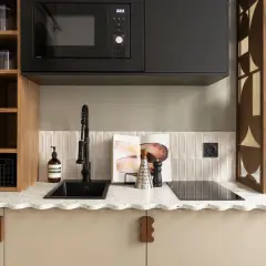 Petite cuisine moderne avec évier noir, plaque de cuisson, micro-ondes et étagères en bois.