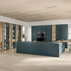 Cuisine moderne avec îlot central bleu canard, armoires intégrées et étagères en bois.