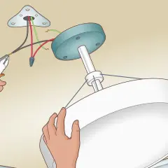 Installation d'un luminaire au plafond. Un fil noir et un fil rouge sont connectés, sans fil de terre, pour le branchement luminaire 2 fils sans terre.