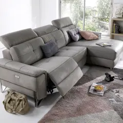 Canapé d'angle gris en cuir, avec repose-pieds déployé. Ce fauteuil relax qui grince est prêt pour un moment de détente.