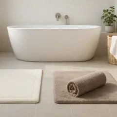 Salle de bain moderne avec baignoire. Deux tapis de bain, un beige roulé, un blanc. Apprenez comment laver un tapis de bain pour une propreté impeccable.
