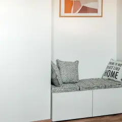 Un coin lecture zen avec un banc blanc, coussins gris et un tableau abstrait. Parfait pour se détendre.