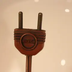 Prise électrique ancienne en bakélite marron avec le logo Mazda. Pour savoir comment reconnaître une lampe Mazda, cherchez cette marque distinctive.