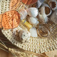 Lunettes de soleil roses, coquillages, bijoux et herbes sèches sur un chapeau de paille.