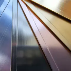 Échantillons de métaux aux reflets variés : argent, cuivre, or. La couleur des métaux est mise en valeur par la lumière.