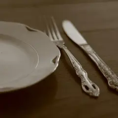 Une assiette blanche et des couverts en argent ornés, prêts pour un repas. Apprenez comment nettoyer des couverts en argent pour qu'ils brillent.