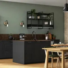 Cuisine style bistrot avec étagères métalliques, plantes vertes, îlot central noir et table en bois.
