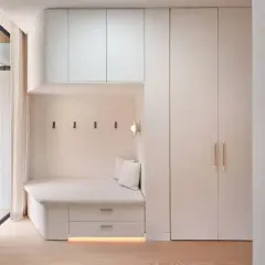 Banquette intégrée avec rangements sous pente, murs clairs, parquet bois.
