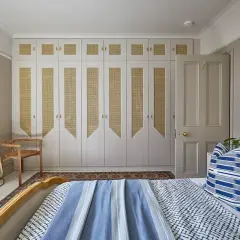 Comment éclairer une pièce sans fenêtre : un mur de placards en rotin et des appliques murales diffusent une lumière douce.