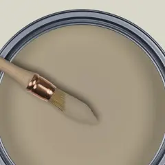 Pinceau trempé dans une peinture beige grège, prêt à transformer un espace.