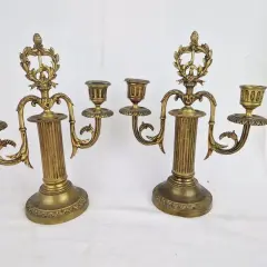 Deux candélabres en bronze doré, ornés de guirlandes et de cannelures, illustrent comment reconnaître un chandelier ancien par leur style et leur patine.