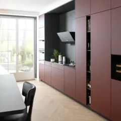 Cuisine moderne avec des armoires bordeaux allant jusqu'au plafond, un îlot central gris, et une grande fenêtre lumineuse.
