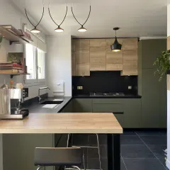 Cuisine moderne avec meubles vert olive, bois clair et plan de travail noir.