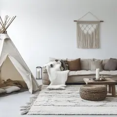 Un coin jeux enfant salon avec une tente tipi, coussins douillets et un tapis douillet.