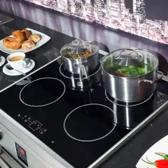 Plaque à induction avec deux casseroles, tasses de café et viennoiseries.