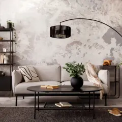 Salon au **couleur mur style industriel**, avec canapé gris, fauteuil orange, étagères noires et table basse.