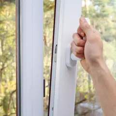 Main tenant ouvrant une fenêtre pour comment purifier l'air de sa maison. L'air frais extérieur entre, apportant la nature.