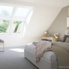 Chambre mansardée cocooning baignée de lumière naturelle grâce aux fenêtres de toit. Un lit douillet, un fauteuil invitant et un bureau complètent cet espace paisible.
