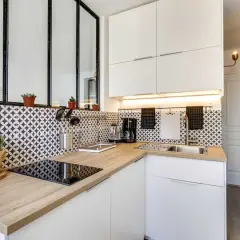 Coin cuisine moderne avec plan de travail en bois, carrelage graphique noir et blanc, et électroménager.