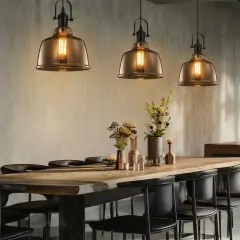 Trois luminaires suspendus de style industriel, parfaits pour fabriquer un luminaire suspendu unique. Ambiance chaleureuse au-dessus d'une table en bois.