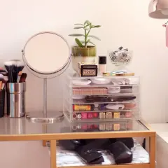 Coiffeuse organisée avec miroir, pinceaux, maquillage et plante.