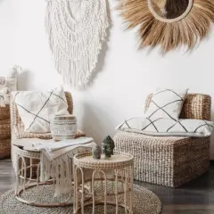 Salon au thème bohème chic avec fauteuils en rotin, coussins graphiques, macramé mural et bougeoirs sculptés.