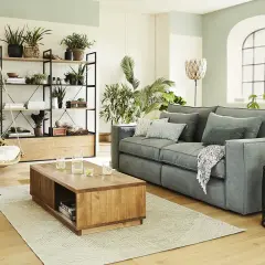 Un salon moderne et lumineux, dominé par des tons verts et naturels. Un canapé gris confortable, une table basse en bois, une balancelle en rotin et de nombreuses plantes créent une ambiance zen. La couleur salon est apaisante.