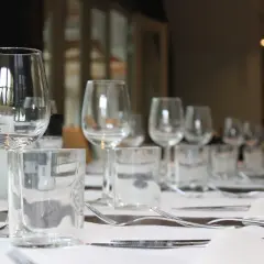 Un élégant placement verre table, prêt pour un repas. Des verres à vin et à eau, des couverts et des serviettes attendent les convives.