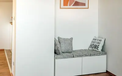Un coin lecture zen avec un banc blanc, coussins gris et un tableau abstrait. Parfait pour se détendre.