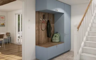 Aménagement placard entrée bleu pastel avec banc, patères pour manteaux et raquette, et sac à dos vert. Un escalier blanc est visible à droite.