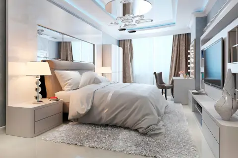Chambre moderne avec un grand lit douillet, un miroir au dessus du lit reflétant le plafond design et une télévision murale.