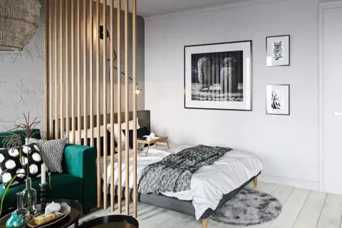 Chambre moderne séparée par un paravent en bois, avec un canapé vert et un lit.