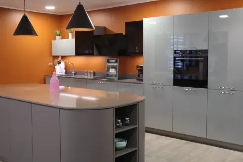 Cuisine moderne avec îlot central gris et meubles muraux bleus. Le vide sanitaire derrière le meuble cuisine est discret.
