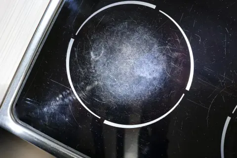 Gros plan sur une plaque à induction noire, marquée par de nombreuses rayures sur la zone de cuisson.
