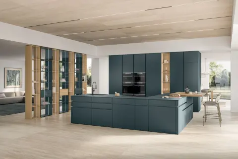 Cuisine moderne avec îlot central bleu canard, armoires intégrées et étagères en bois.