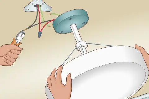 Installation d'un luminaire au plafond. Un fil noir et un fil rouge sont connectés, sans fil de terre, pour le branchement luminaire 2 fils sans terre.