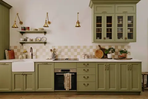Cuisine vert d'eau avec évier, plaque de cuisson, four et placards en bois.
