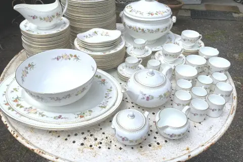 Vaste service de porcelaine à la cendre d'os, orné de délicates fleurs, comprenant théière, tasses, bols et assiettes.