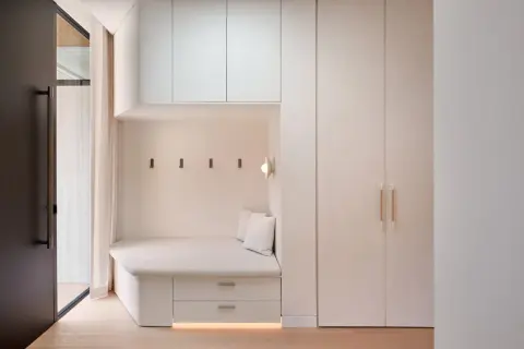 Banquette intégrée avec rangements sous pente, murs clairs, parquet bois.