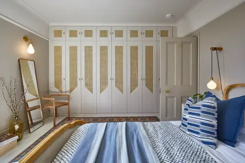 Comment éclairer une pièce sans fenêtre : un mur de placards en rotin et des appliques murales diffusent une lumière douce.