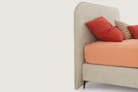 Tête de lit beige avec coussins rouges et orange.