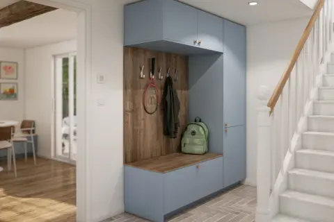 Aménagement placard entrée bleu pastel avec banc, patères pour manteaux et raquette, et sac à dos vert. Un escalier blanc est visible à droite.
