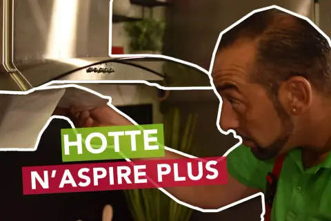 Un homme examine sa hotte neuve qui n'aspire pas. Il vérifie le filtre, cherchant la cause du problème.