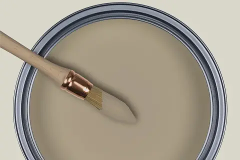 Pinceau trempé dans une peinture beige grège, prêt à transformer un espace.
