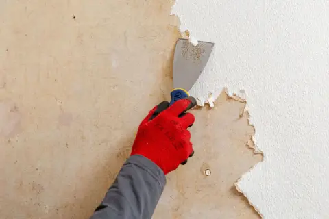 Main tenant, une spatule pour décoller du papier peint. Une astuce de grand-mère pour un chantier propre.