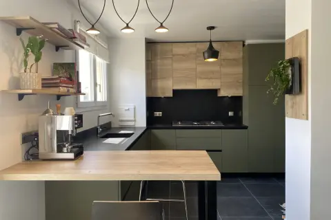 Cuisine moderne avec meubles vert olive, bois clair et plan de travail noir.
