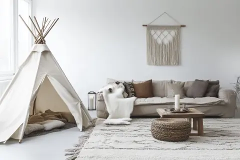 Un coin jeux enfant salon avec une tente tipi, coussins douillets et un tapis douillet.