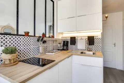 Coin cuisine moderne avec plan de travail en bois, carrelage graphique noir et blanc, et électroménager.