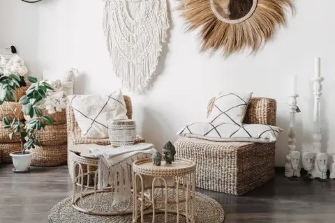 Salon au thème bohème chic avec fauteuils en rotin, coussins graphiques, macramé mural et bougeoirs sculptés.